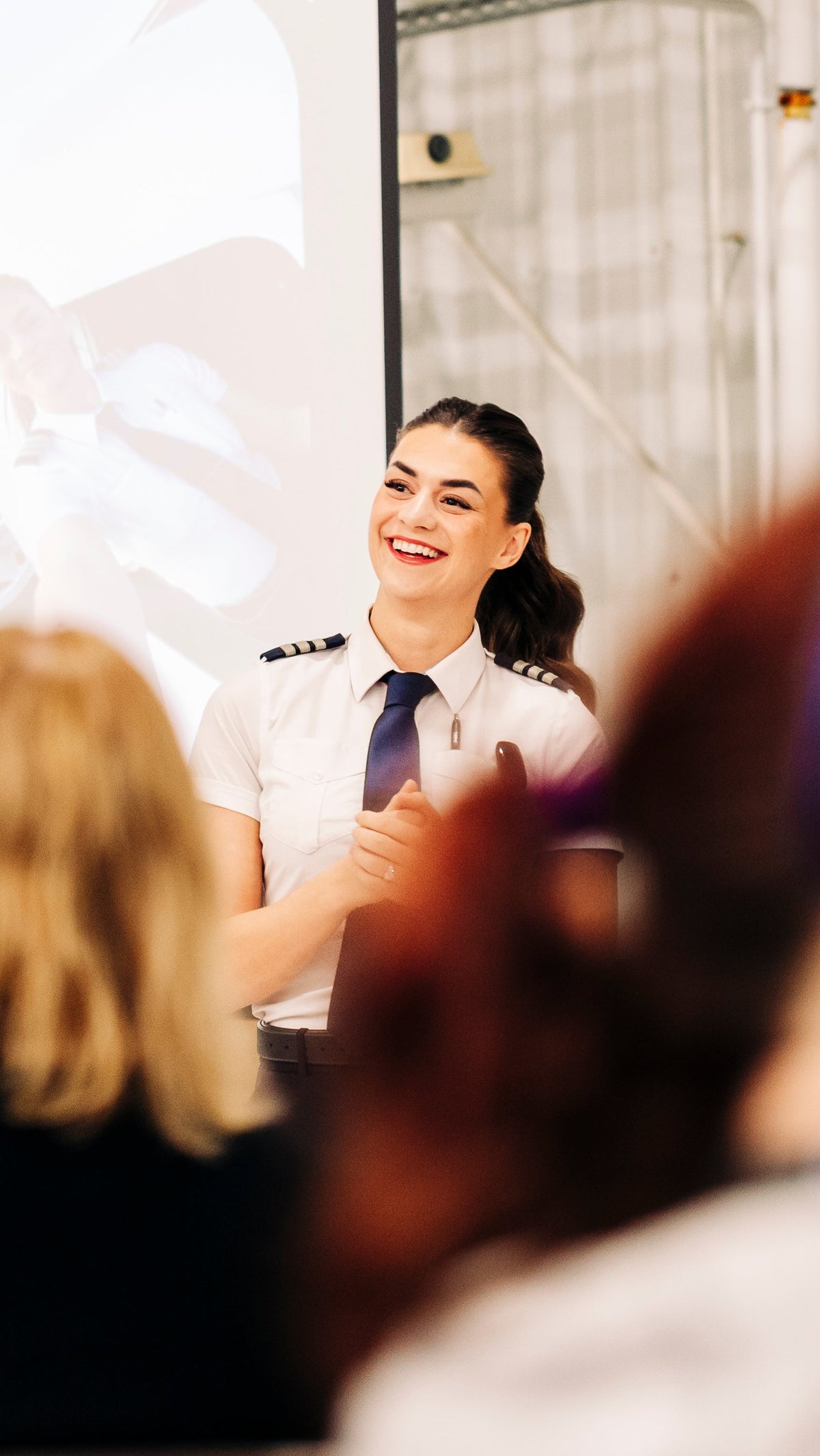 Ava in her airline pilot uniform, smiling as she presents to an audience
